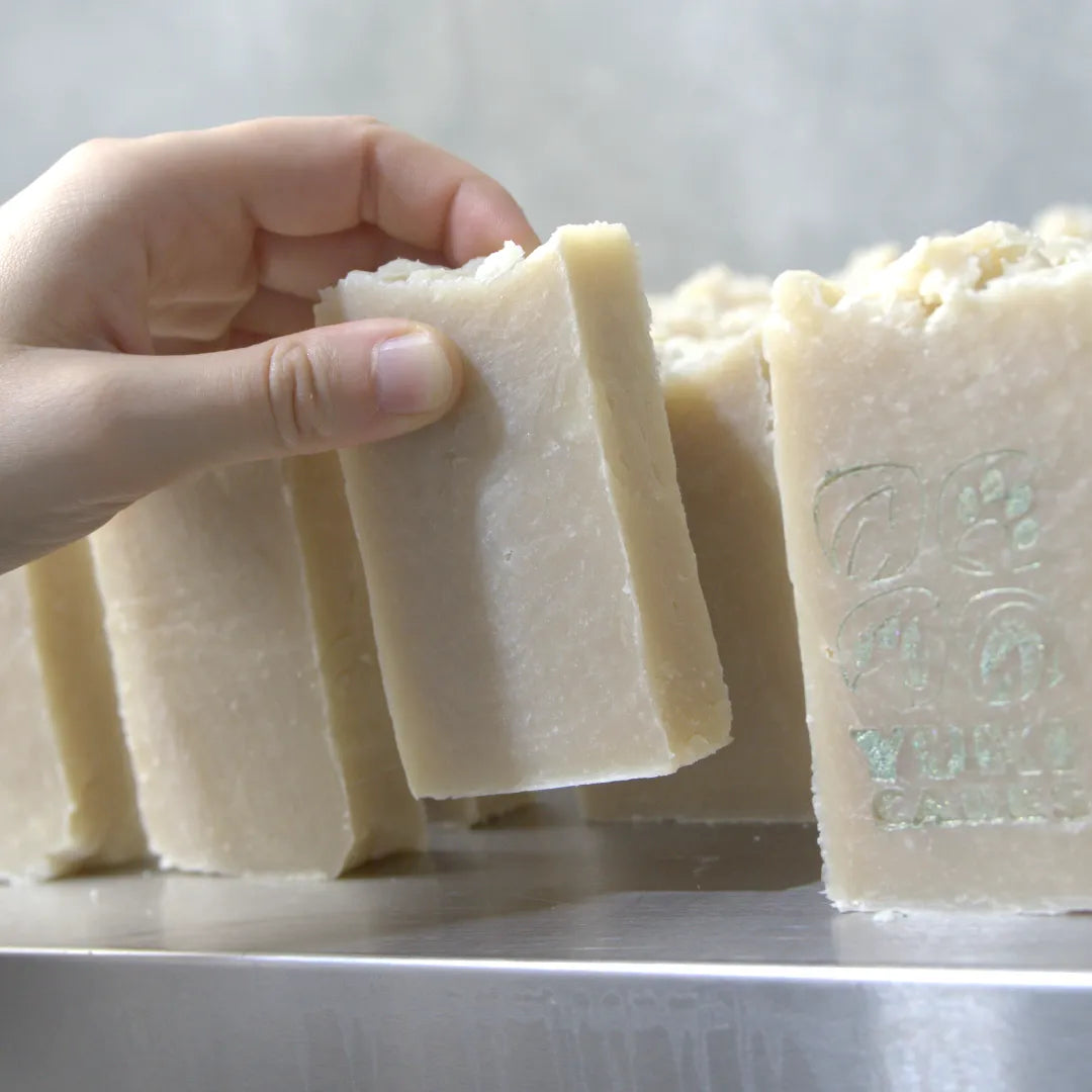 Eine Hand greift nach einem Stück handgemachter Seife, die mit natürlichen Zutaten gefertigt wurde.