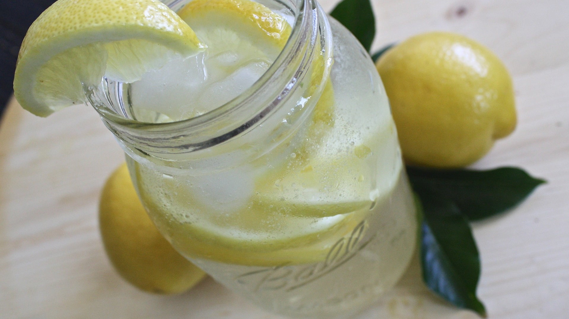 Einmachglas mit Wasser, Eis und Zitronenspalten