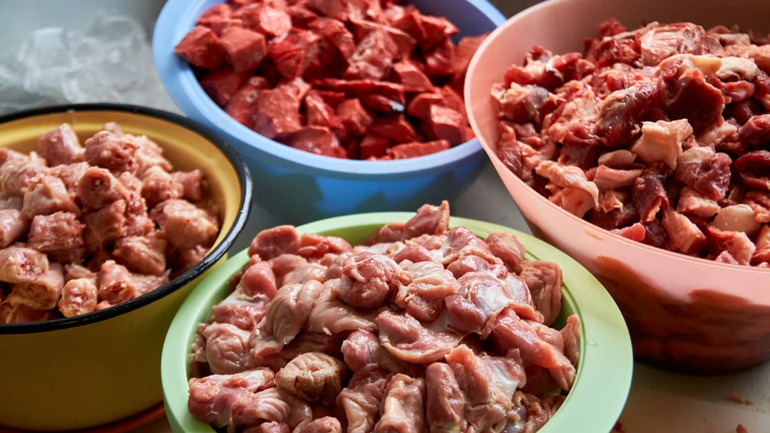 Verschiedene Schalen sind mit frischem, rohem Fleisch gefüllt und stehen auf einem Tisch zur Zubereitung bereit.