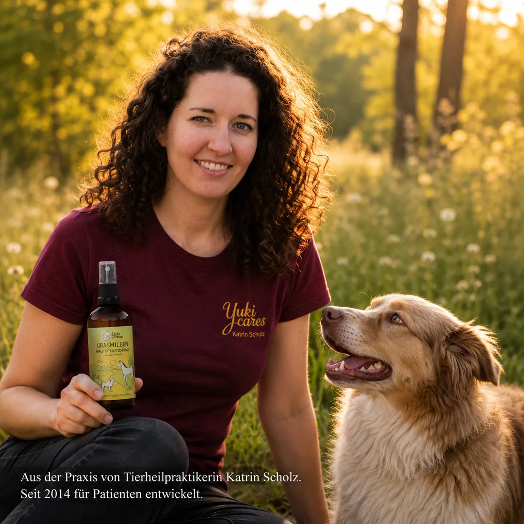 Katrin Scholz hält ein Spray in der Hand, während ihr Hund neben ihr in der sonnigen Wiese sitzt. | © Yuki Cares