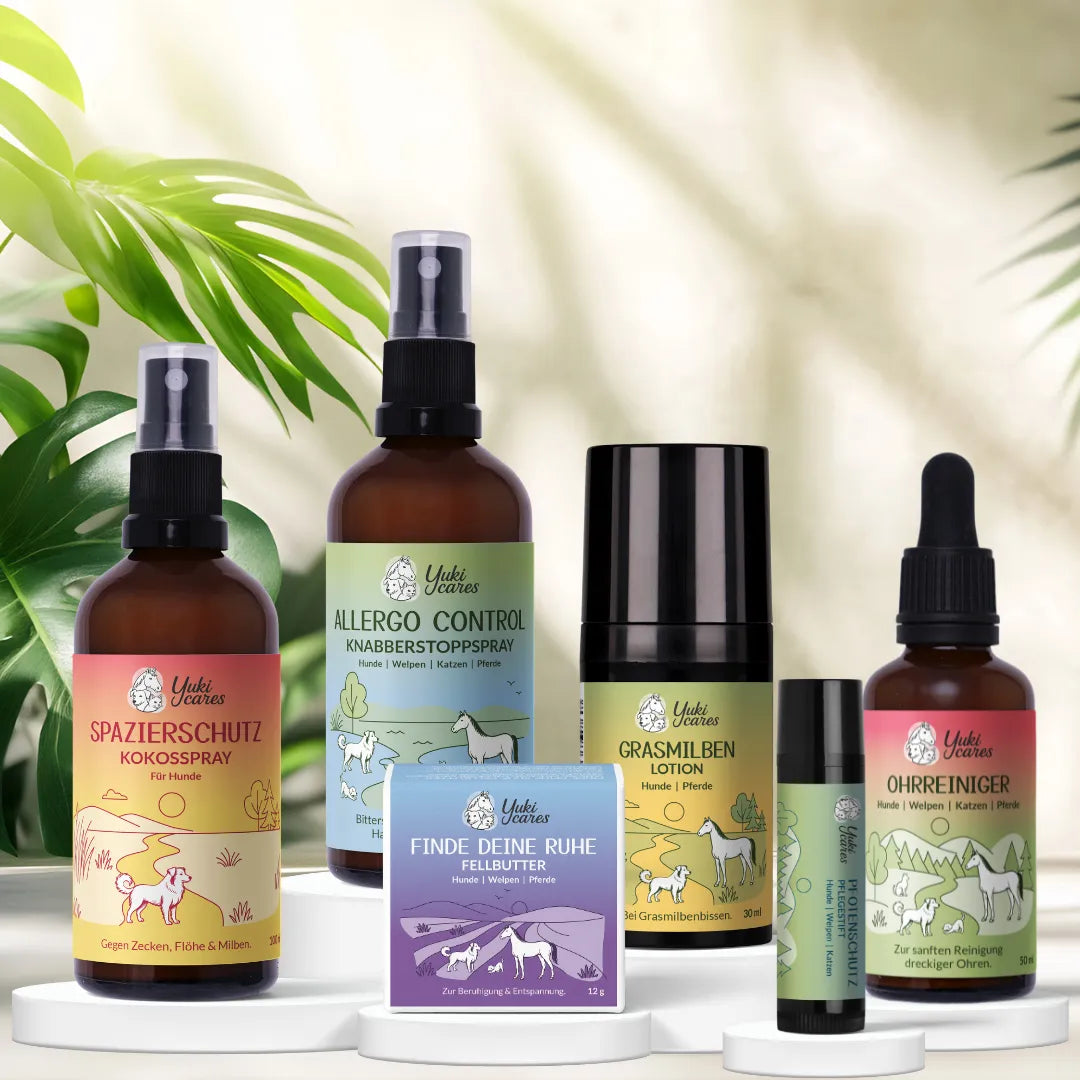 Verschiedene Haustierpflegeprodukte von Yuki Cares stehen vor grünen Blättern auf einem weißen Hintergrund.